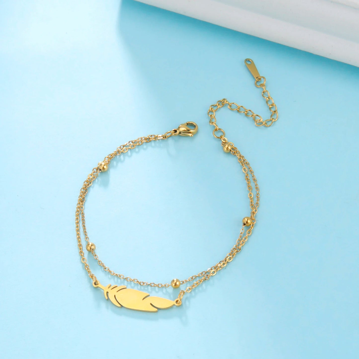 Tels des éclats d'écume dorée et argentée, ces bracelets à plumes se posent avec grâce sur la peau, rappelant la légèreté des brises marines