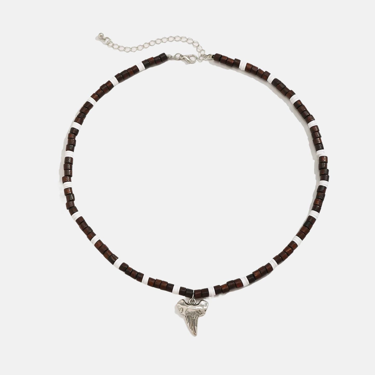 Ce collier en perles marron et blanches, orné d'un pendentif en forme de dent de requin, évoque l'âme aventureuse des marins des temps anciens