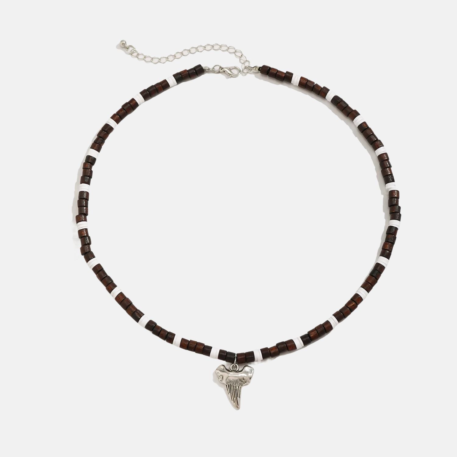 Ce collier en perles marron et blanches, orné d'un pendentif en forme de dent de requin, évoque l'âme aventureuse des marins des temps anciens