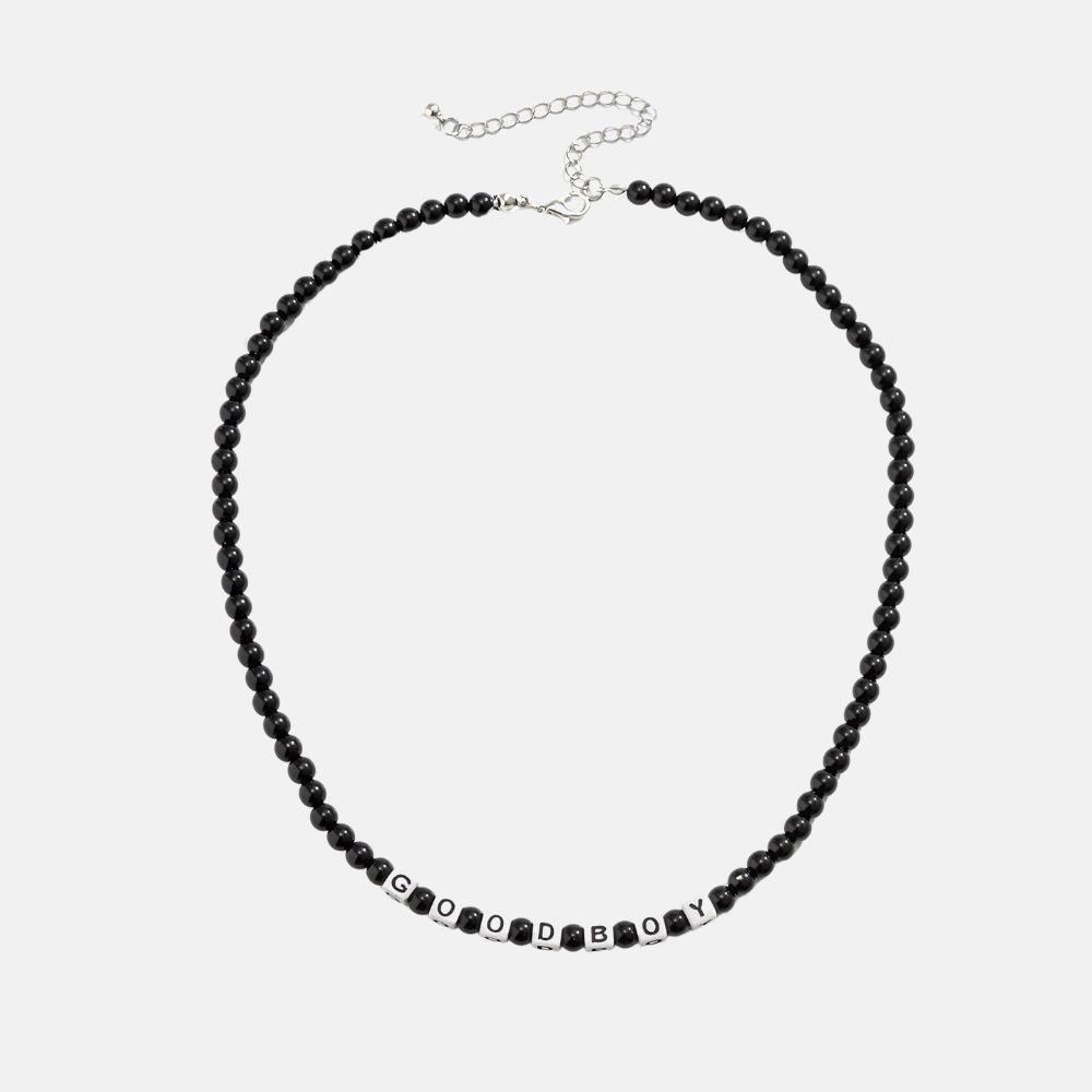 Ce collier en perles noires, avec ses lettres blanches formant "GOOD BOY", évoque l'élégance brute et l'esprit aventureux des marins sillonnant les vastes océans