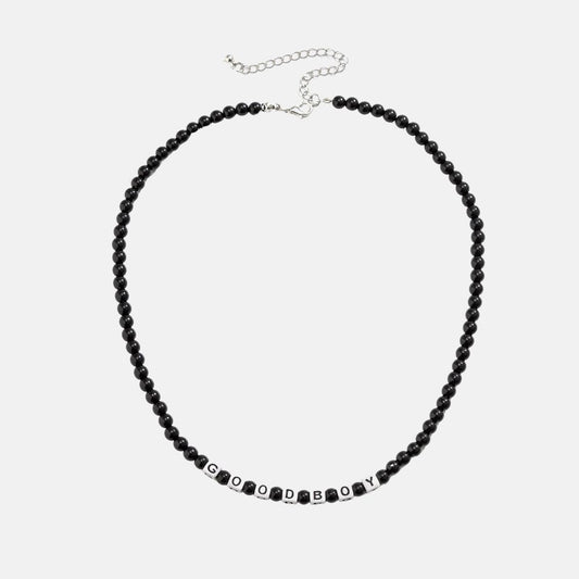 Ce collier en perles noires, avec ses lettres blanches formant "GOOD BOY", évoque l'élégance brute et l'esprit aventureux des marins sillonnant les vastes océans