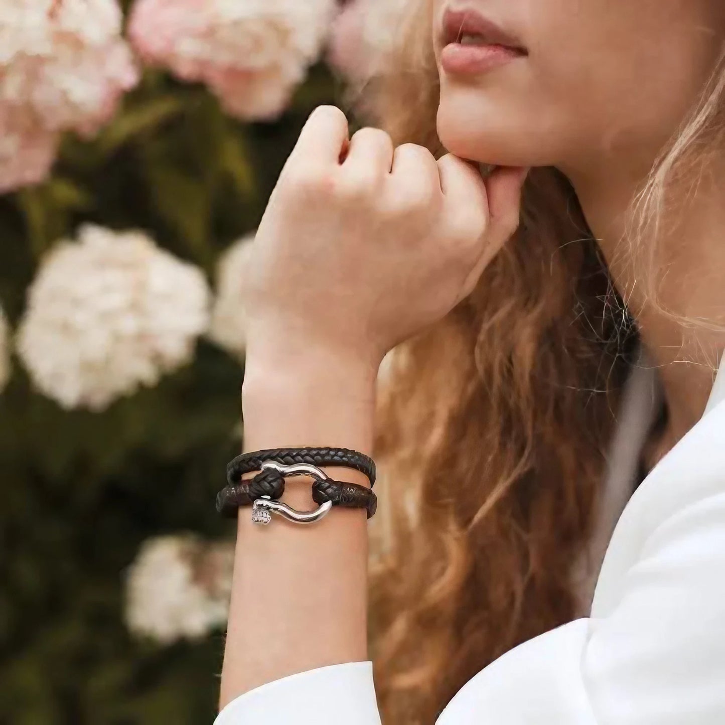 Un bracelet en cuir tressé marron, orné d'une élégante attache en acier inoxydable, alliant robustesse et raffinement