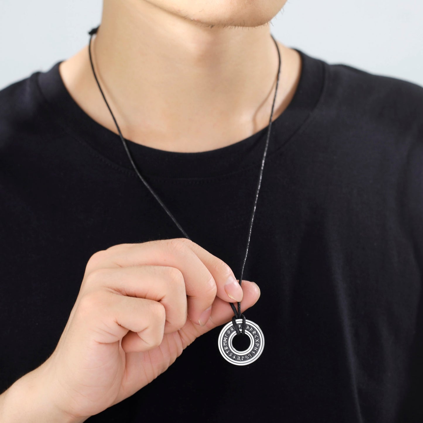 Ce pendentif en argent, gravé de runes mystérieuses, est suspendu à un élégant cordon noir, évoquant la profondeur et le mystère des océans