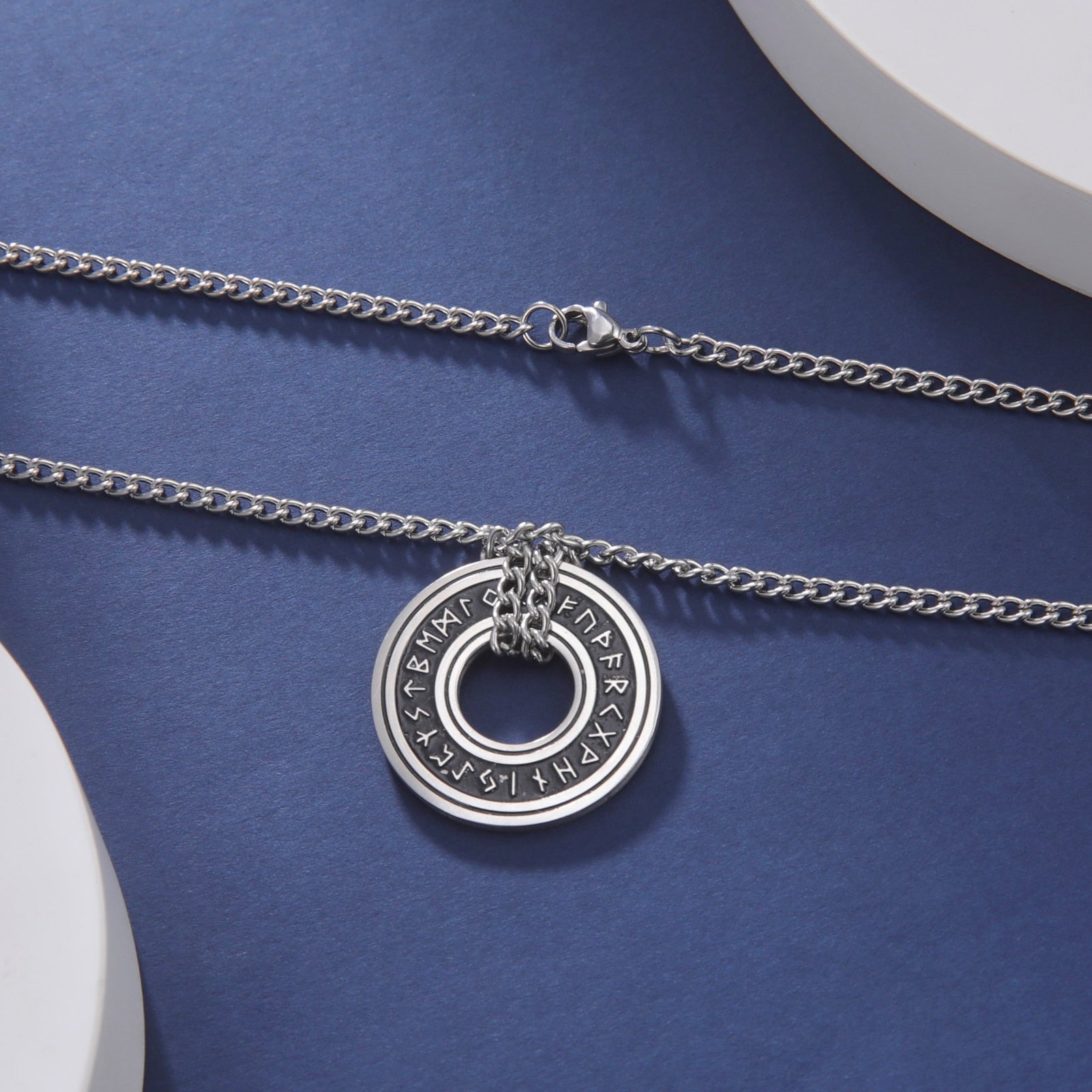 Ce pendentif en argent, gravé de runes mystérieuses, est suspendu à un élégant cordon noir, évoquant la profondeur et le mystère des océans