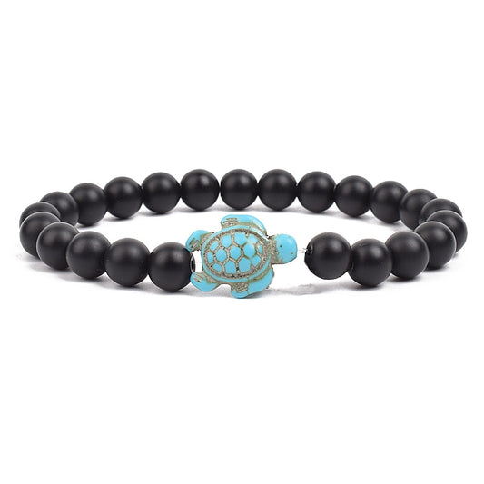 Ce bracelet de perles, orné d'une tortue délicate, brille comme un trésor rare trouvé dans les profondeurs des océans, prêt à enchanter celui qui le porte