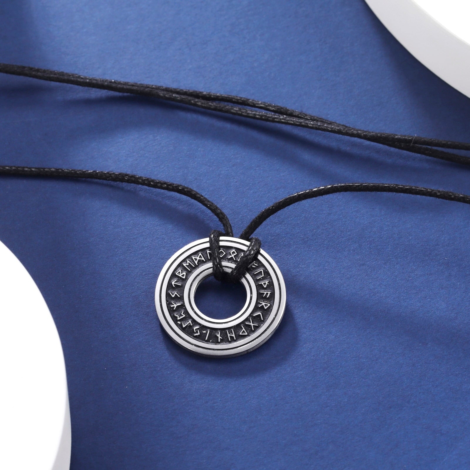Ce pendentif en argent, gravé de runes mystérieuses, est suspendu à un élégant cordon noir, évoquant la profondeur et le mystère des océans