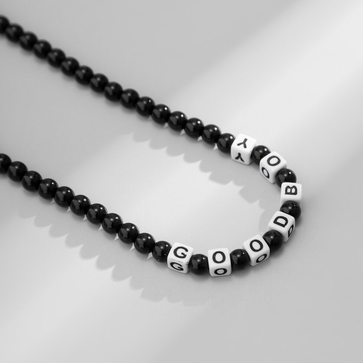 Ce collier en perles noires, avec ses lettres blanches formant "GOOD BOY", évoque l'élégance brute et l'esprit aventureux des marins sillonnant les vastes océans