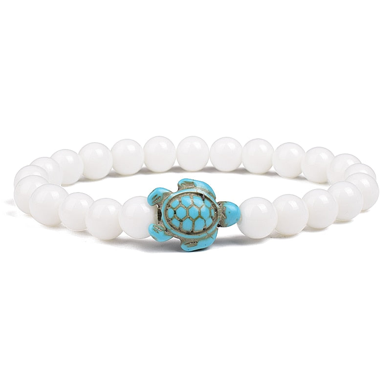 Ce bracelet de perles, orné d'une tortue délicate, brille comme un trésor rare trouvé dans les profondeurs des océans, prêt à enchanter celui qui le porte