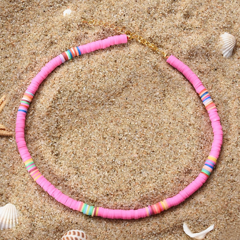 Ce collier en perles roses et multicolores évoque les couleurs chatoyantes d'un coucher de soleil sur l'océan