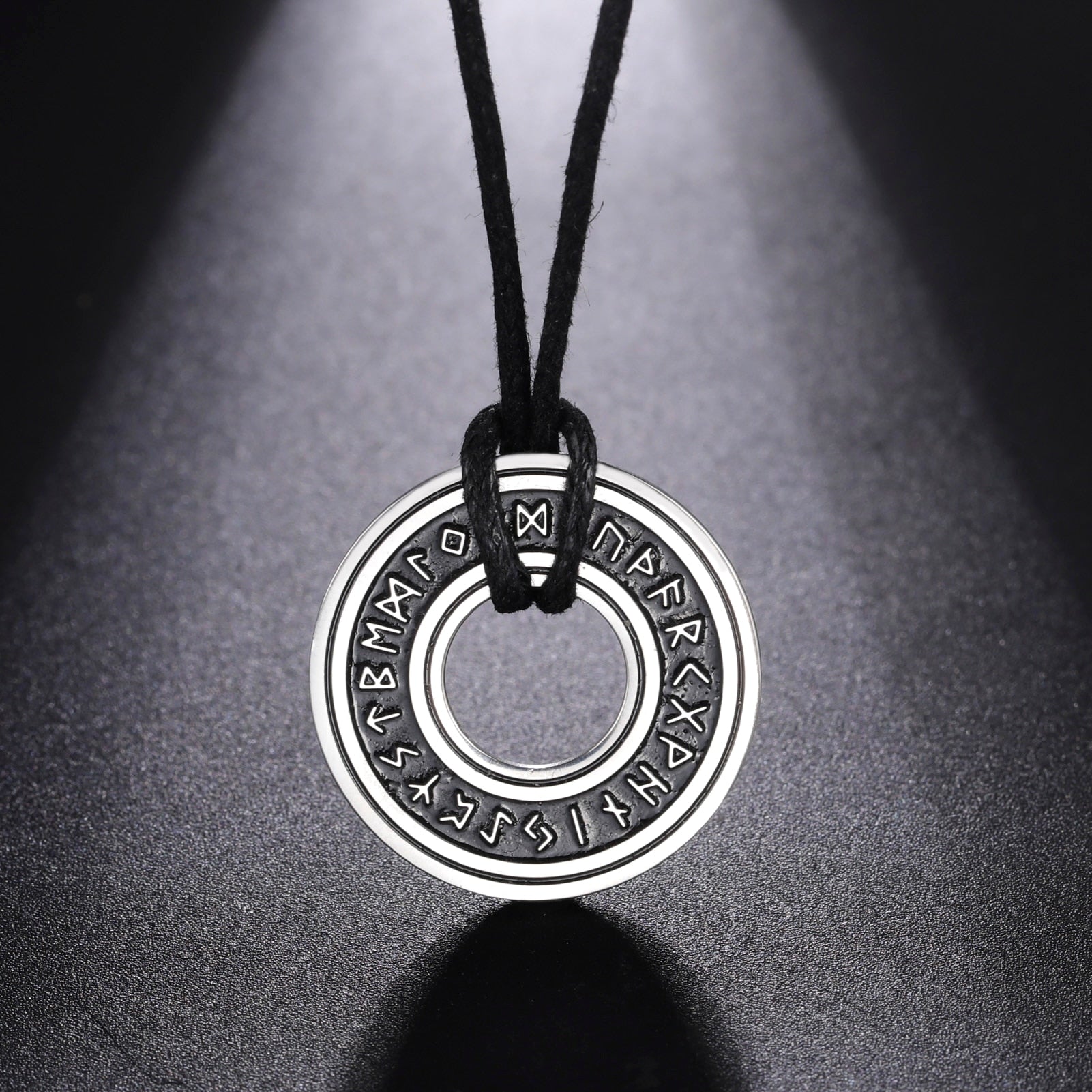Ce pendentif en argent, gravé de runes mystérieuses, est suspendu à un élégant cordon noir, évoquant la profondeur et le mystère des océans