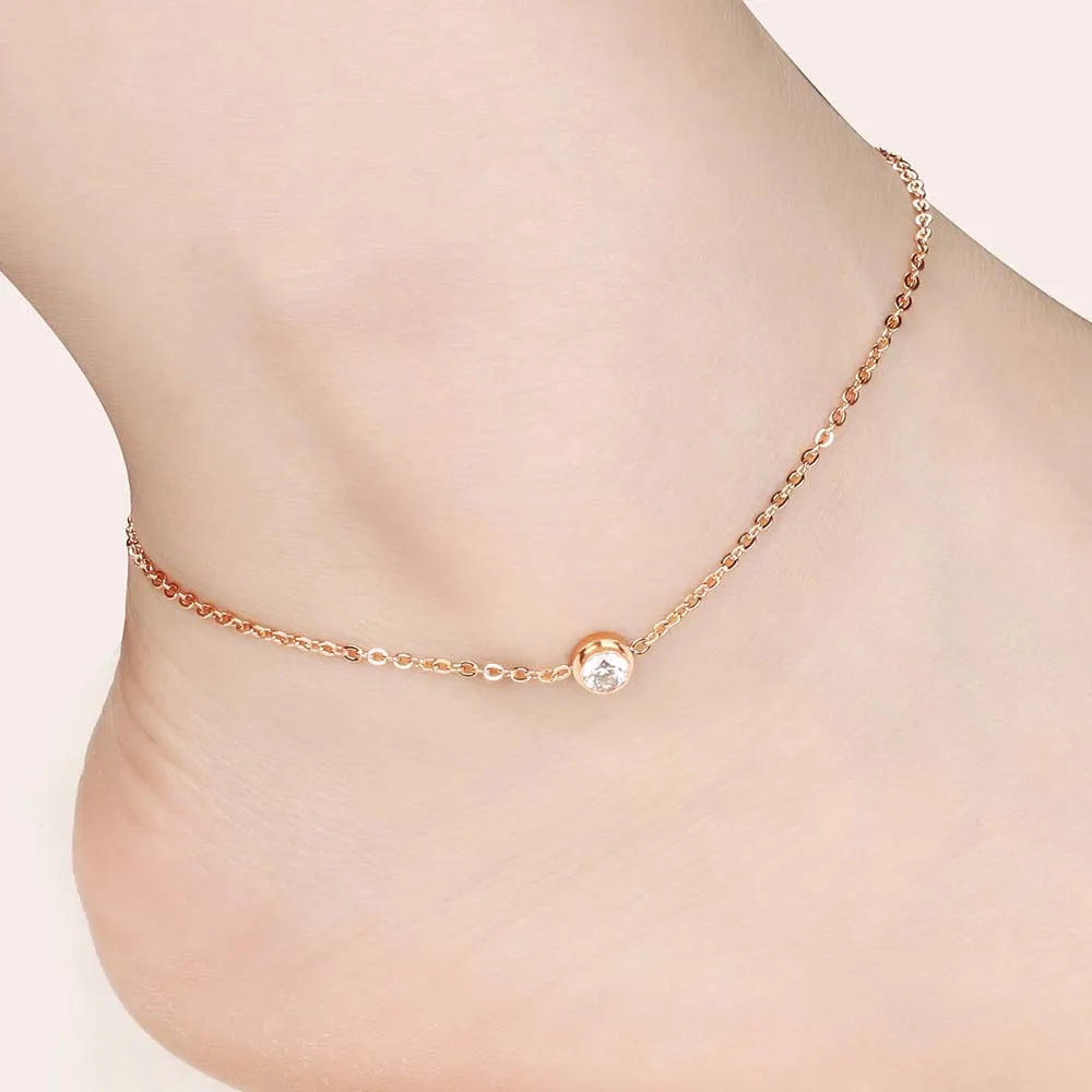 Comme une goutte d'or pure, ce bracelet fin enlace la cheville avec la douceur d'une vague au coucher du soleil, portant en son cœur une gemme scintillante comme l'étoile du matin sur la mer calme