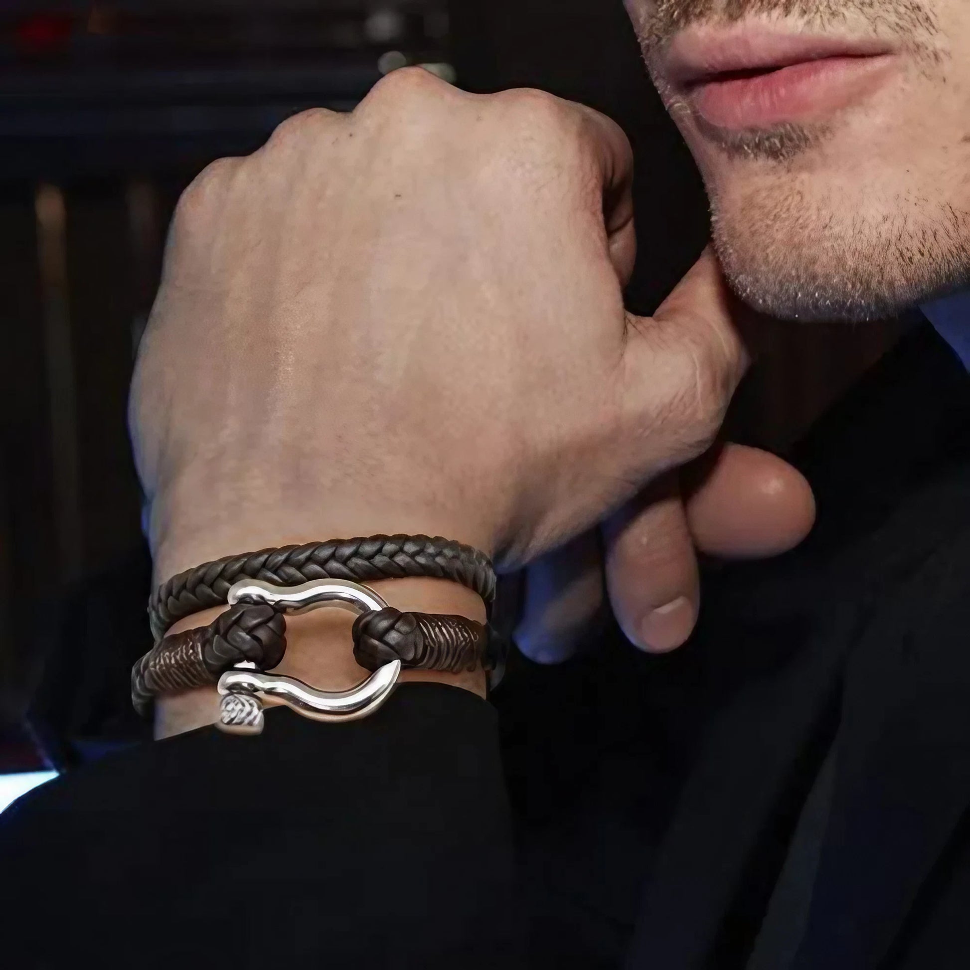 Un bracelet en cuir tressé marron, orné d'une élégante attache en acier inoxydable, alliant robustesse et raffinement